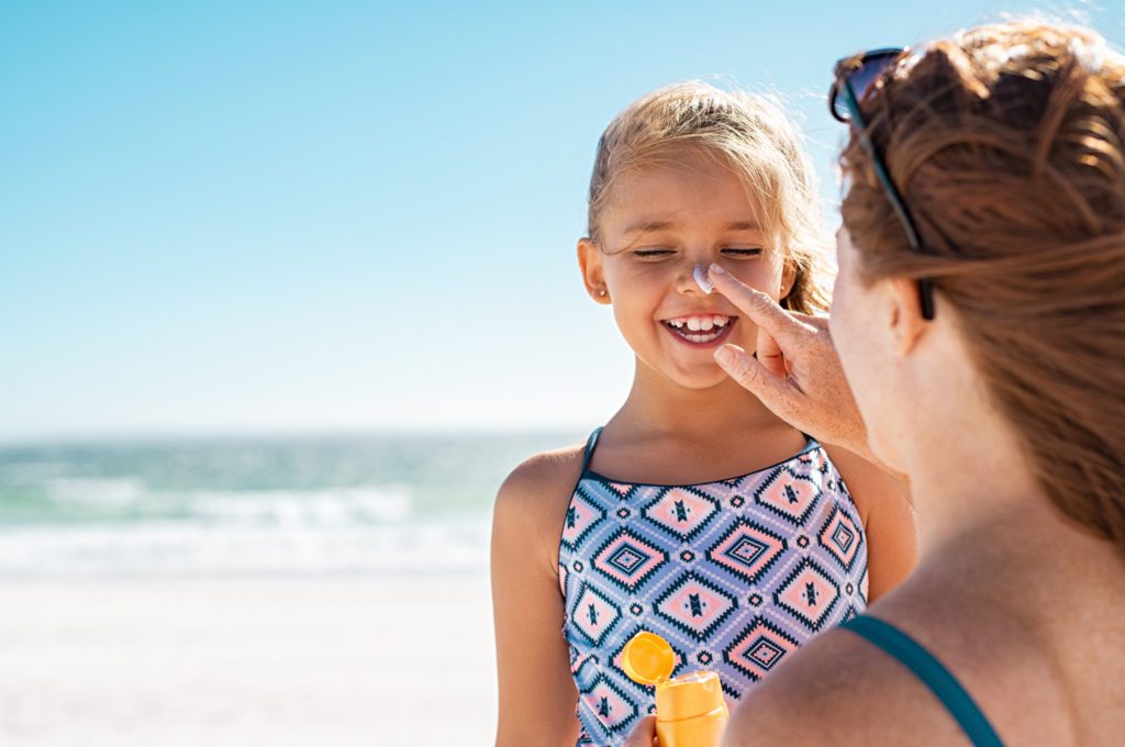 mother putting sunscreen on daughter at the beach - one of the best myrtle beach things to do with kids